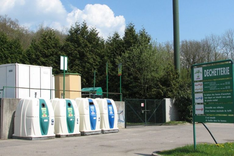 Quatre conteneurs de recyclage situés dans une déchetterie. 