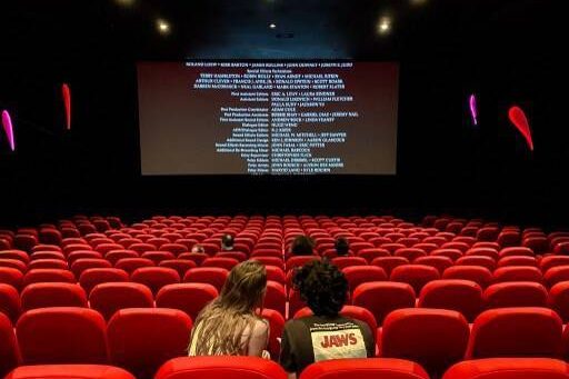 Salle de cinéma avec des sièges rouges et un écran affichant des crédits de film.